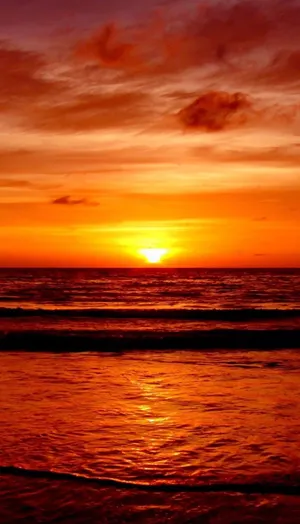 A Breathtaking Shot Of A Spectacular Red Sunset Over The Ocean Wallpaper