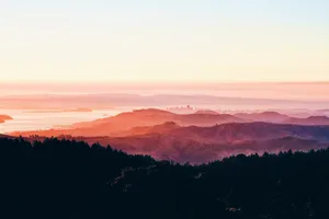 A Breathtaking Sunset Off Of A Mountain Range Wallpaper