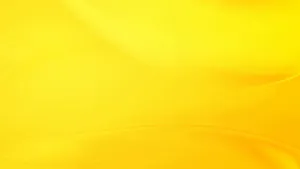 A Bright, Pastel Yellow Laptop Resting On A Wooden Desk Wallpaper