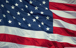 A Brightly Colored U.s. Flag Ripples In The Breeze Wallpaper