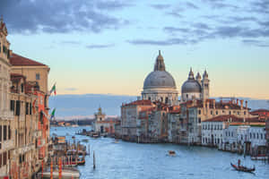 A Canal With Buildings And A Church In The Background Wallpaper