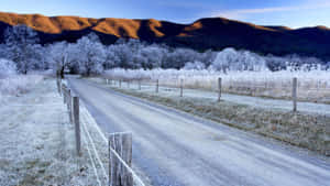 A Car Driving Cautiously On An Icy Road During Winter Wallpaper