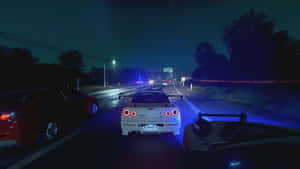 A Car Driving Down The Road At Night Wallpaper