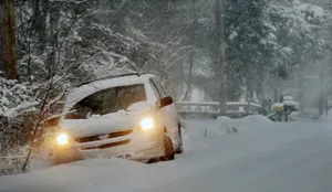 A Car Driving On A Snowy Road In A Winter Landscape Wallpaper