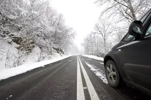 A Car Driving Through A Snowy Winter Road Wallpaper