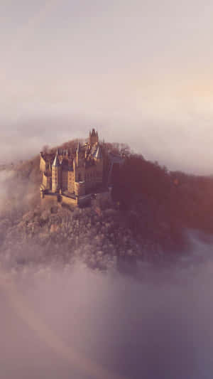 A Castle Is Sitting On Top Of A Hill In The Fog Wallpaper