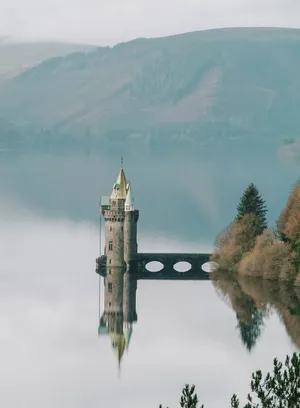 A Castle Sits On Top Of A Lake Wallpaper