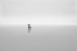 A Chair Sits On A Solitary Island In The Middle Of The Ocean Wallpaper