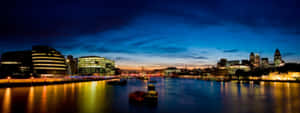 A City At Night With A River And Buildings Wallpaper