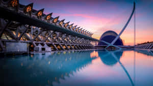 A City At Sunset With A Large Building And A Pool Wallpaper