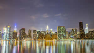 A City Skyline Is Reflected In A Body Of Water Wallpaper