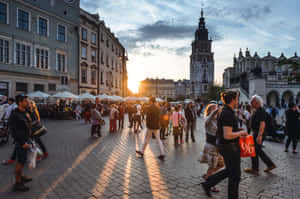 A City Square With People Walking Around At Sunset Wallpaper