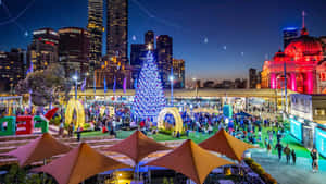 A City With A Christmas Tree And People In The Middle Wallpaper