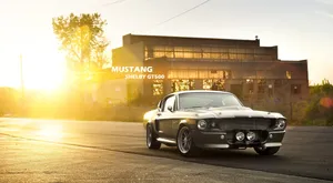 A Classic Mustang Is Parked In Front Of A Building Wallpaper