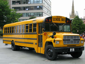 A Classic Yellow School Bus Parked On A Sunny Day Wallpaper