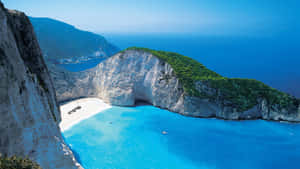 A Cliff With Blue Water And A Beach Wallpaper