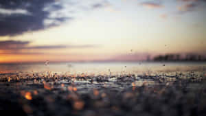 A Close Up Of A Water Droplet On The Ground Wallpaper