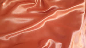 A Close Up Of An Orange Satin Fabric Wallpaper