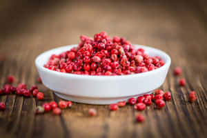 A Close-up Of Pink Peppercorns On A Wooden Surface Wallpaper