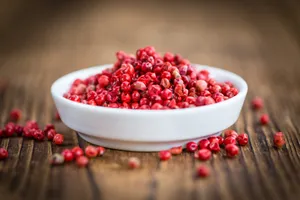 A Close-up Of Pink Peppercorns On A Wooden Surface Wallpaper