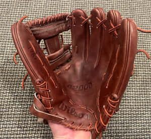 A Close-up View Of High-quality Baseball Gloves On A Wooden Surface Wallpaper