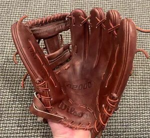 A Close-up View Of High-quality Baseball Gloves On A Wooden Surface Wallpaper