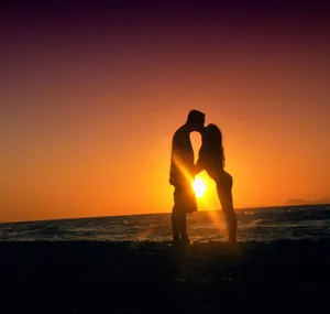 A Couple Enjoying A Romantic Walk On The Beach At Sunset Wallpaper