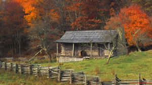 A Cozy Cabin Nestled Among Colorful Autumn Trees Wallpaper
