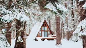 A Cozy Winter Cabin Nestled In The Snow Wallpaper