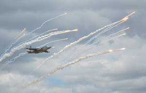 A Daring Fighter Plane Soaring Through A Blue Sky Wallpaper