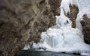 A Daring Ice Climber Ascending A Frozen Waterfall Wallpaper