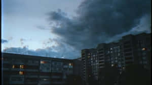 A Dark Sky Over A City With Buildings Wallpaper