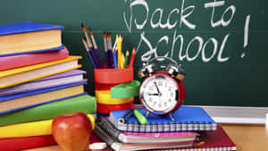 A Desk With Books, Pencils, And An Alarm Clock Wallpaper