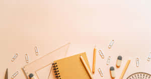 A Desk With Pens, Pencils, A Notebook And A Pencil Case Wallpaper