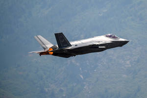 A F-15 Fighter Jet Flying Over A Mountain Wallpaper