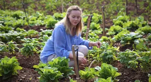 A Farmer Tending To The Vast Green Field In Organic Farming Wallpaper