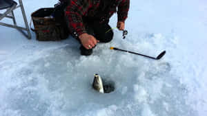 A Fisherman Enjoys A Peaceful Ice Fishing Session On A Frozen Lake Wallpaper