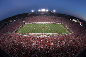 A Football Stadium With A Large Crowd At Night Wallpaper