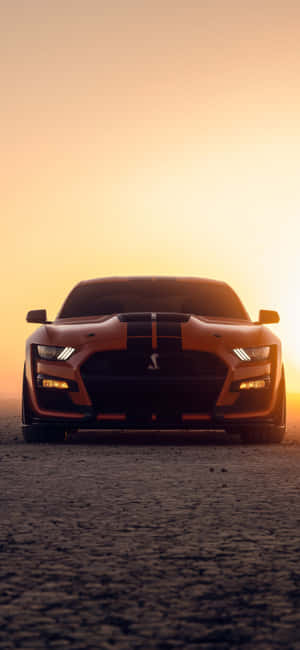 A Ford Mustang Gt Is Sitting In The Desert At Sunset Wallpaper