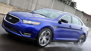 A Ford Taurus Moving On The Street At High Speed, Showcasing Its Sleek Design And Powerful Features. Wallpaper