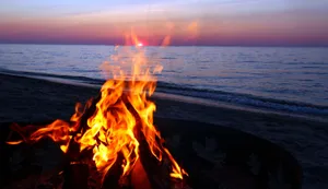 A Glowing Beach Bonfire Under Moonlit Sky Wallpaper