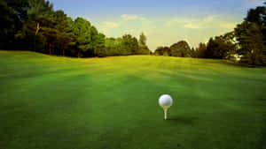 A Golfer Preparing To Swing While Overlooking A Beautiful Course At Sunset. Wallpaper