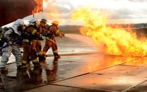 A Group Of Firefighters Are Battling A Fire Wallpaper