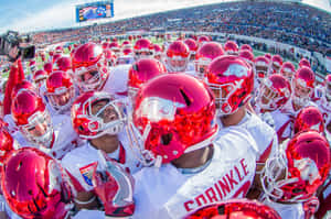 A Group Of Football Players Huddle Together Wallpaper