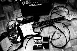 A Guitar And Amp On A Wooden Floor Wallpaper