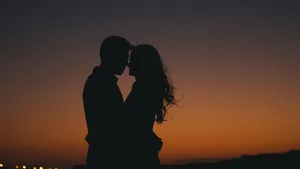A Heart Formed By Rose Petals On A Sandy Beach With Ocean Waves In The Background Wallpaper