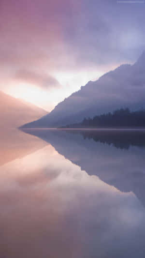 A Lake With Mountains And Fog Reflected In It Wallpaper