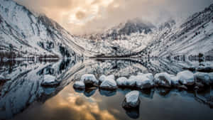 A Lake With Rocks And Snow In The Background Wallpaper