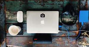 A Laptop, Phone, And Other Items On A Wooden Table Wallpaper