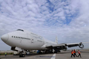 A Large Airplane On The Tarmac With People Walking Around It Wallpaper